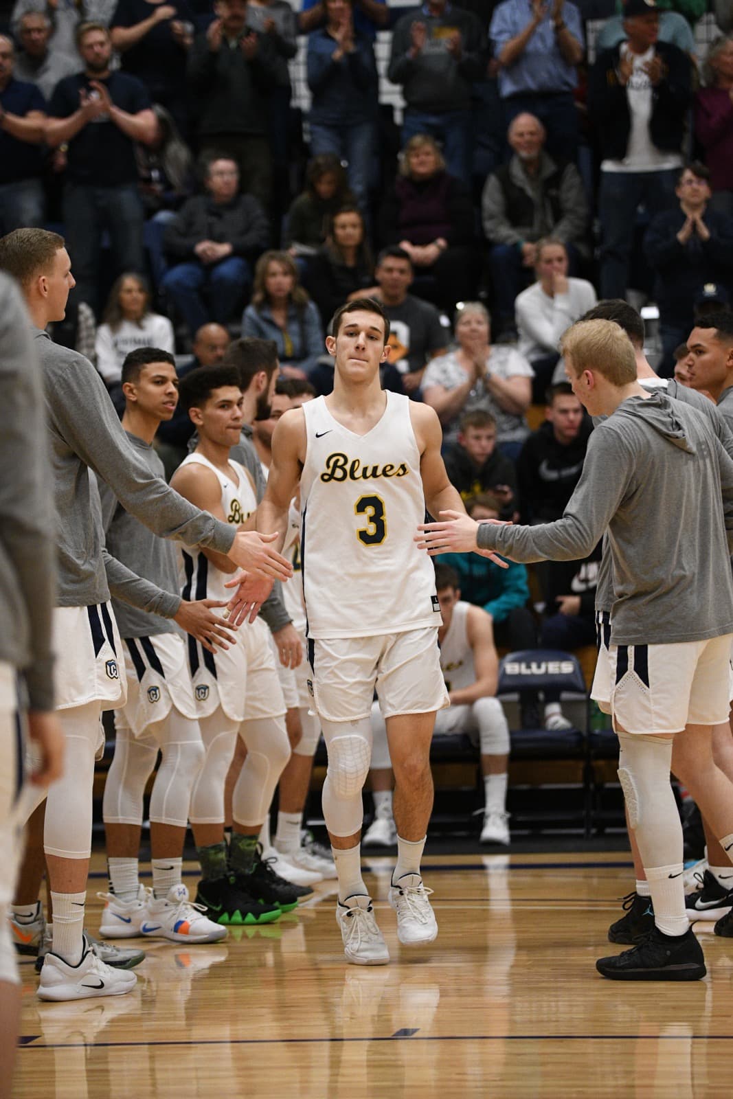Joey Hewitt walking through a high-five line during a Whitman College Blues basketball game